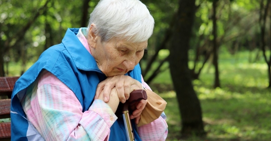 Senior woman sits pensively on a park bench